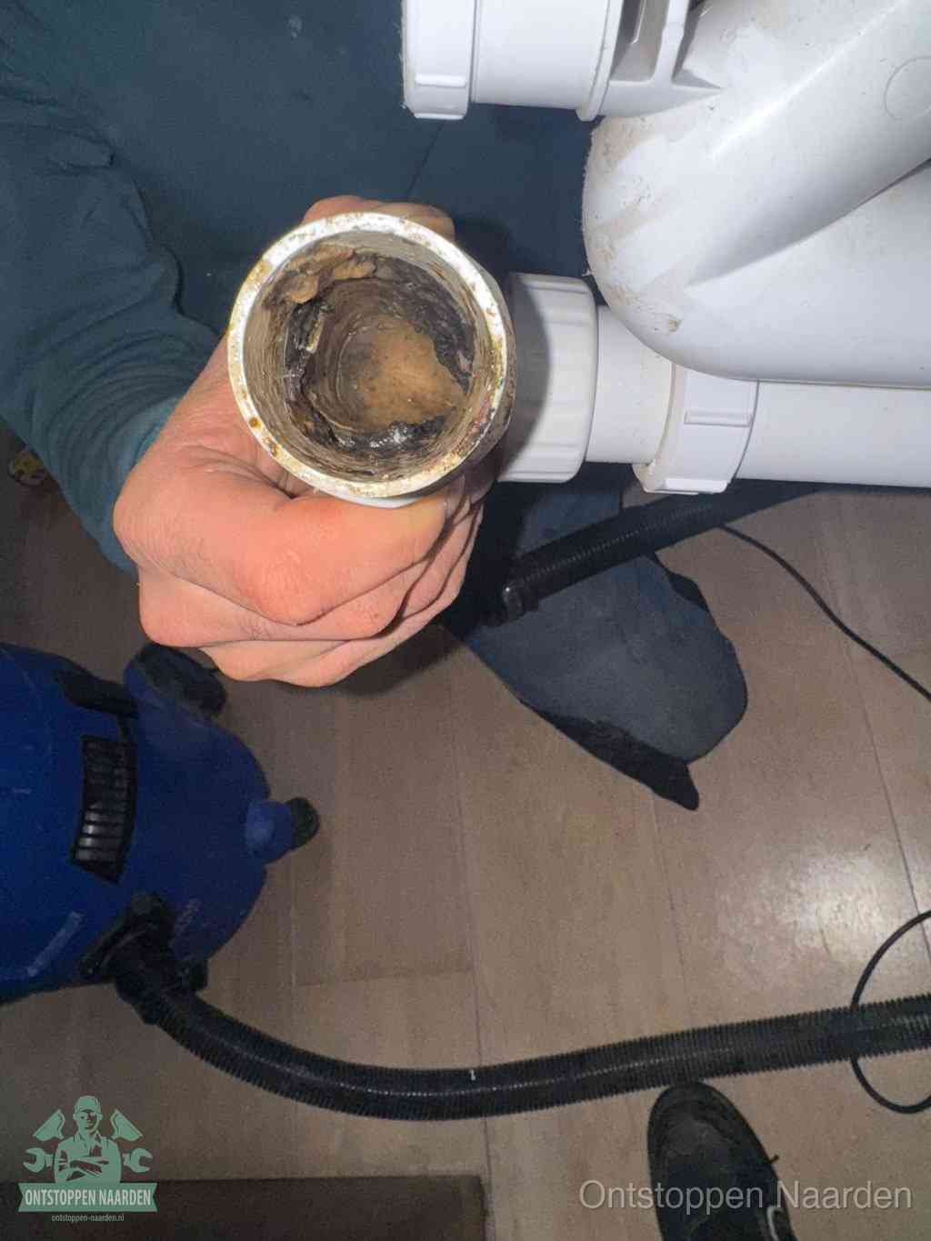 Een losgekoppeld afvoerbuisstuk dat van binnen volledig is dichtgeslibd, het gevolg van een verstopping te lang laten zitten in Naarden
