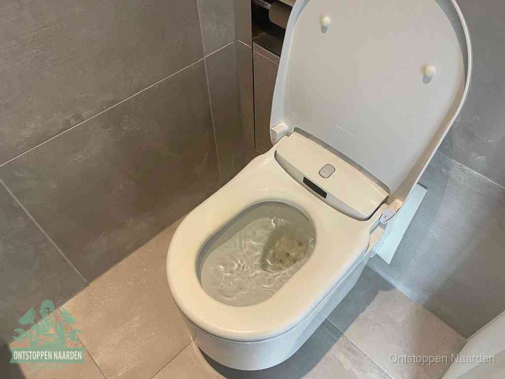 Een toiletpot vol troebel water met drijvend papier en restanten, de meest voorkomende oorzaak van een verstopte wc in Naarden