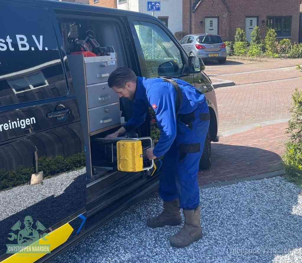 Een monteur pakt apparatuur uit de bedrijfsbus voor service aan huis, het moment om een professional in te schakelen voor een verstopte wc in Naarden