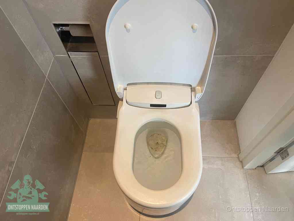 Een wit hangtoilet waarin een prop wc-papier op het water blijft drijven, een duidelijk signaal van een verstopte wc in Naarden