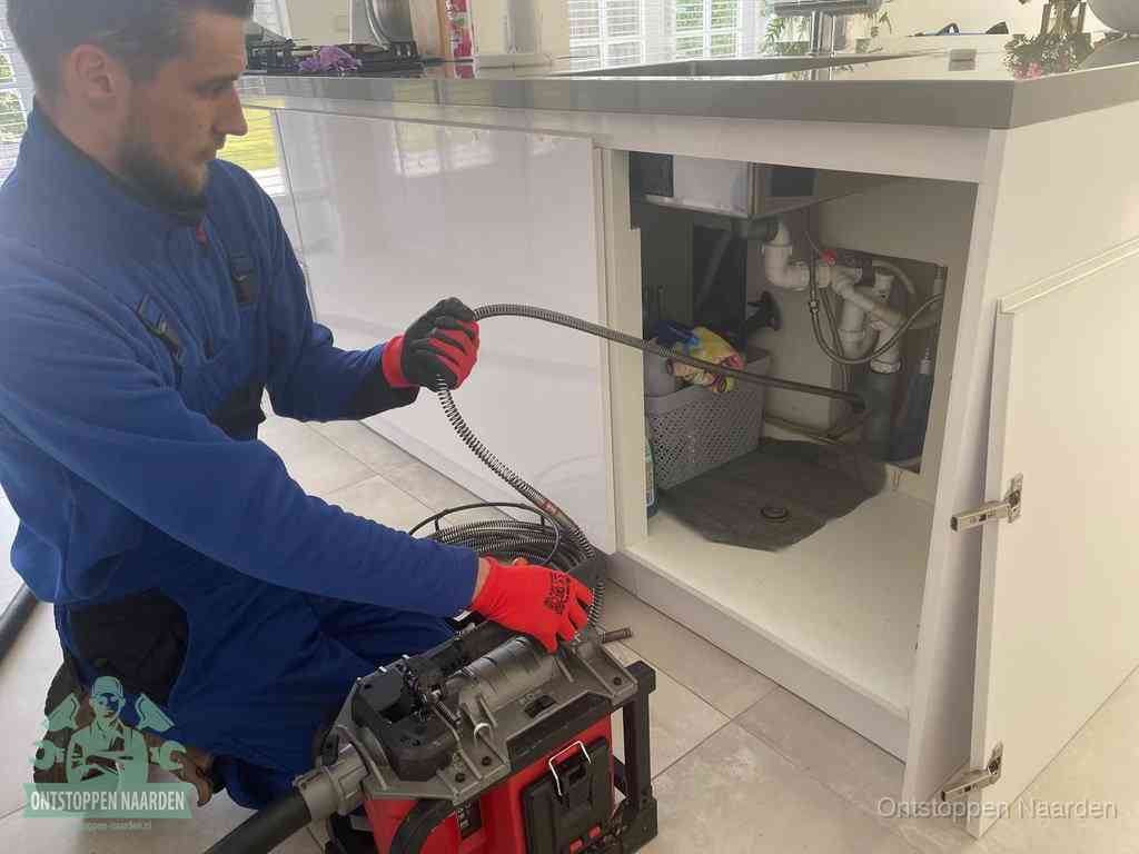 Een monteur reinigt de keukenafvoer grondig met een veermachine om terugkerende gootsteenverstoppingen te voorkomen in Naarden