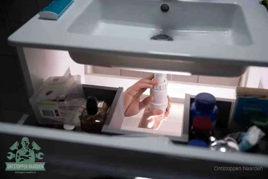 Een pompfles met zeep boven een wastafel in de toiletruimte, de warm water en afwasmiddel-methode om de wc te ontstoppen in Naarden